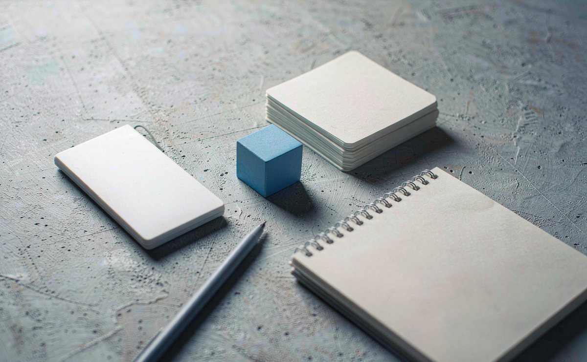 Blank index cards, a desk calendar, a fine liner pen and a pocket calculator on a light grey desk